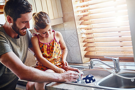 家务是他们家庭日常工作的一部分 一位父亲和他的小女儿在家里一起洗碗图片