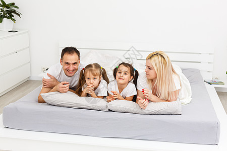 年轻家庭一起在父母的床上休息母亲成人姐姐感情男人女士爸爸孩子们女儿房子图片