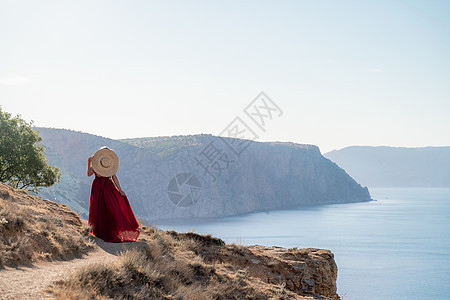 一个穿着红色飞行服的女人 在大海的背景下 飘在风中发抖着天空女性幸福丝绸太阳女孩衣服飞行旅行自由图片