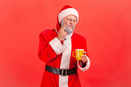 穿着圣达克萨斯服装的灰胡子老人在喝热饮料或冷饮后 牙痛严重 长得一副像图片