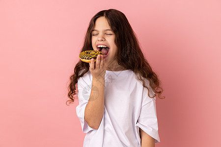 满足的小女孩咬着美味甜甜圈 期待着吃甜点图片