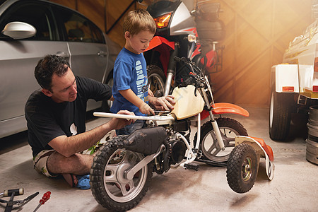 他跟爸爸学了很多东西 父亲和儿子在车库修自行车图片