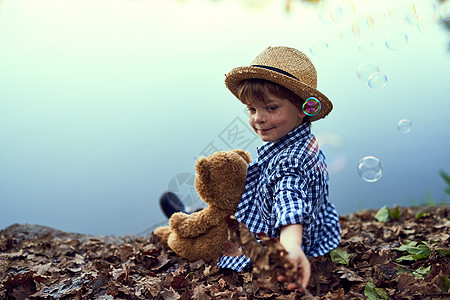 只有他和他的泰迪在大户外 一个小男孩坐在森林里 带着他的泰迪熊图片