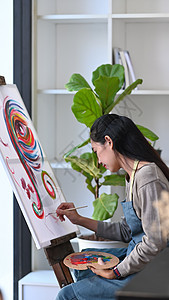 年轻的亚洲女画家 在艺术工作室的画布上画画图片