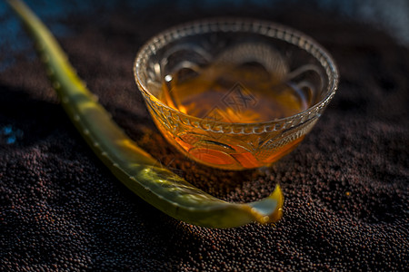 芥子种子为皮肤发光而用面罩遮住 表面涂有芥子籽 aloe Vera 和黑面玻璃碗中的一些蜂蜜香料色素沉着按摩果汁产品排毒酵素收据图片