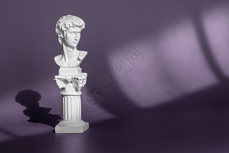 古代雕像头的石膏副本在紫色背景与光影 年轻人的白色大理石头像 米开朗基罗的著名雕像头像 - 来自佛罗伦萨的大卫图片