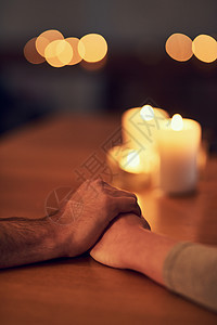 特写了两个无法辨认的人 他们手放在餐桌上 背景里有蜡烛灯 (掌声 “我们被困在黑暗中”)图片