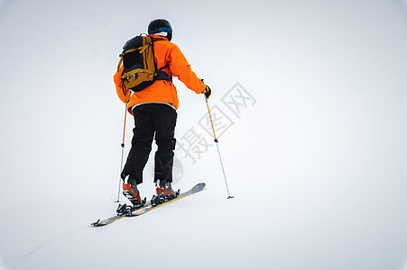 滑雪者爬上雾中的雪覆盖的山脊 背着背包游滑雪旅行图片