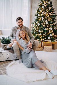 一对相爱的幸福情侣一男一女 一家家庭在明亮的新年内地与圣诞树共聚一堂家居正面母亲喜悦男人父母微笑女士享受沙发背景图片