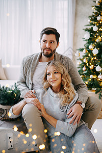 一对相爱的幸福情侣一男一女 一家家庭在明亮的新年内地与圣诞树共聚一堂正面喜悦父母男人父亲享受沙发庆典生活女士背景图片