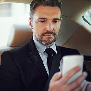 随时随地开展业务 一位坐在汽车后座上使用手机的商务人士图片