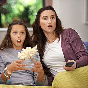 母亲和女儿坐在起居室沙发上看电影 吃爆米花 吃爆米花图片