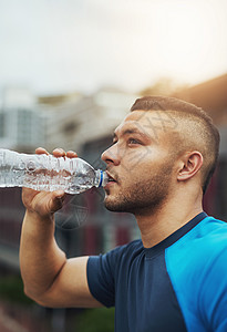 保持水分充沛 一个年轻人喝着水瓶酒出来跑步高清图片