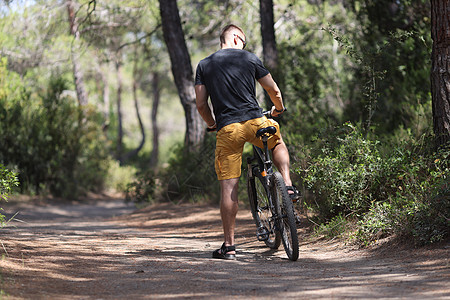 雄心勃勃的骑自行车的人在森林小路上独自坐在自行车上图片
