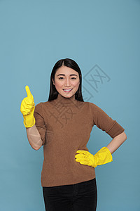 亚洲人笑笑快乐的亚洲女佣拇指 戴着黄色手套图片