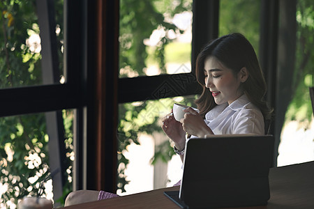 坐在办公室 喝热咖啡的有思想的女商务人士图片