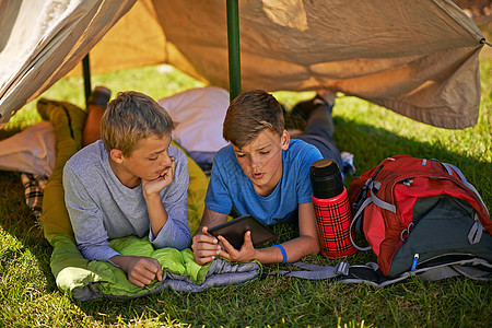看看这个 兄弟 一个年轻男孩在露营时 在数字平板电脑上给朋友看点东西图片