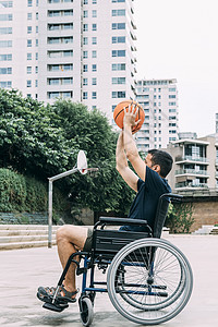 残疾人在轮椅上将球扔到篮子图片