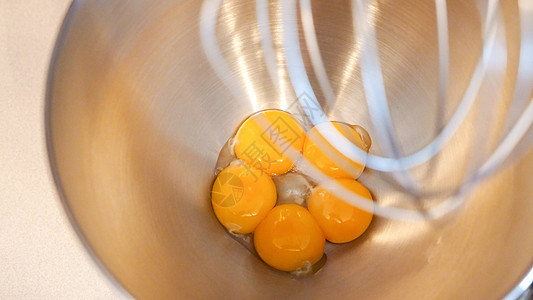 生鸡蛋放在一个金属碗的永久性搅拌机里 在厨房搅拌机里准备配糖的蛋黄混合器杂货店食谱作品烹饪搅拌面团框架面包师面包图片