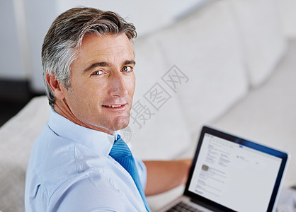 我是一个有商业计划的人 一个成熟商务人士的肖像 坐在沙发上时使用笔记本电脑图片