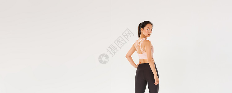 全长专注而积极的年轻亚洲女孩 身材苗条完美 在健身房训练 从后面看 时髦女运动员的后视转向相机 白色背景广告运动装肌肉健美身体跑图片