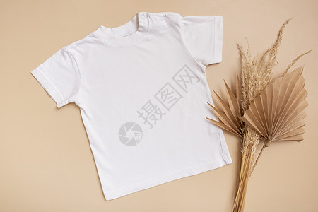 白色婴儿 T 恤顶视图 米色背景上的徽标或设计模型 带棕榈叶的平躺童装图片