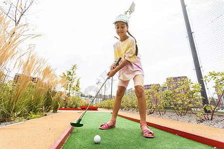 美丽的小女孩玩迷你高尔夫运动高尔夫球乐趣微笑课程俱乐部闲暇快乐训练游戏图片