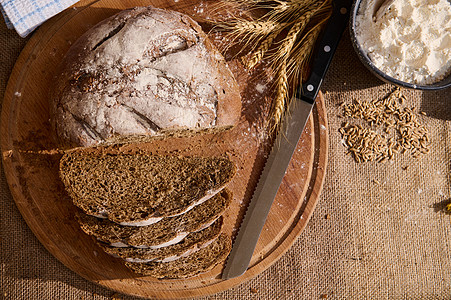 炸馒头片顶端的新鲜面包 木板上有碎屑 小麦小粉片和薄布桌布上零散的谷物背景