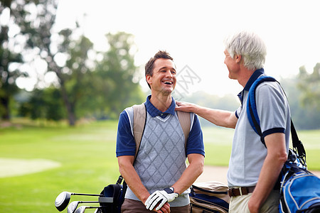 男高尔夫球手与父亲交谈 男高尔夫球手站在高尔夫球场上与他的父亲交谈图片