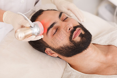 男子在美容诊所接受面部皮肤护理治疗服务卫生电频率男人化妆品电疗客户工作温泉胶原图片