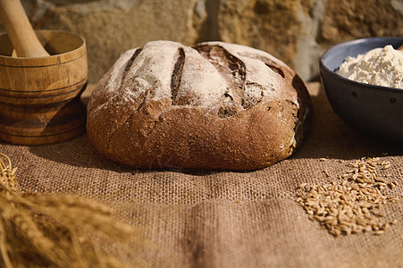 在粗麻布桌布上用自制新鲜烘焙小麦面包 小麦小穗和烘焙配料制成的食品组合物图片