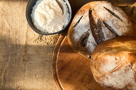 鲜烤土制全谷物和多谷物面包 在木板上盛有小麦花粉和白面粉图片