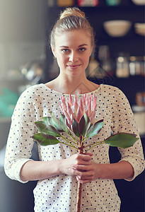 一位美丽的年轻女子的肖像 站在她的厨房里拿着一朵蛋白质花 她长得很漂亮图片
