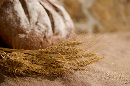 有选择性地关注小麦小麦小粒子和模糊的自制全谷物 新鲜烤面包放在桌边面上加薄饼图片