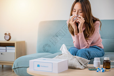 亚裔年青冷冰冷生病的女孩在沙发上用纸纸打喷嚏病人毯子发烧女士组织女性过敏悲伤鼻子流感图片
