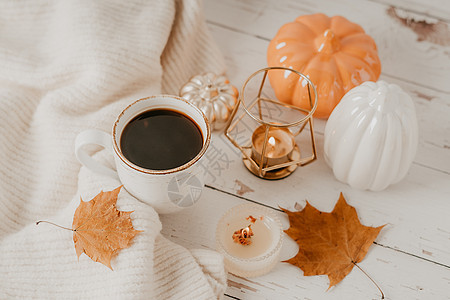 静物的细节 一杯茶或咖啡 南瓜 蜡烛 白桌背景上带叶子的早午餐 舒适房子里的家居装饰 秋季周末的概念 落叶和家居装饰感恩树叶毛衣图片