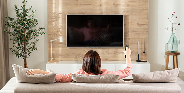 沙发上的女孩在现代客厅里 在电视上换频道图片