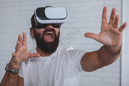 使用VR眼镜的兴奋男人创新享受虚拟现实电子游戏齿轮潮人商业同事眼镜惊愕图片