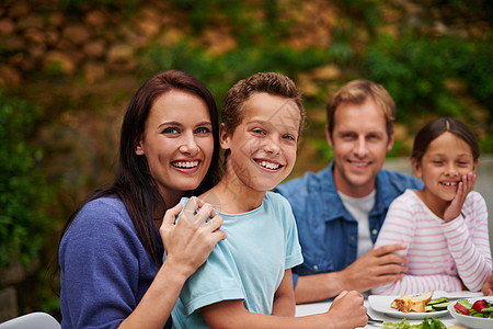 一个微笑的家庭在院子上享受一顿大餐的肖像 食物和家庭时刻图片