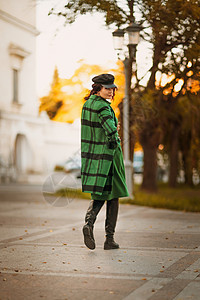 一位优雅时尚的黑发女性的户外时尚肖像 模特戴着时尚的帽子 穿着绿色连衣裙 秋天在欧洲城市的日落时分摆姿势羊毛配件外套骆驼奢华女士图片