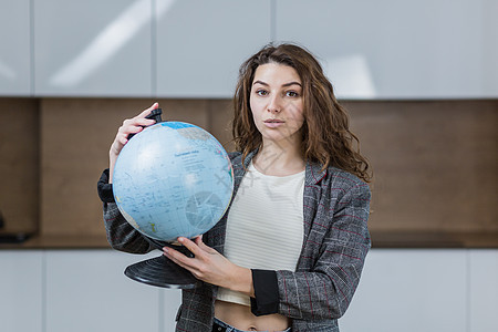 远程教授在线地理课的年轻女教师的肖像 她拿着地球仪 指着乡村地球仪 看着相机图片