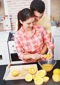 来点新鲜的果汁 一个快乐的年轻夫妇在厨房里煮橙汁图片