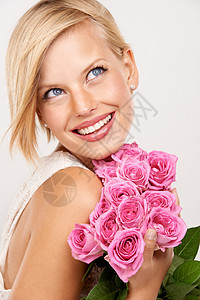 她的美丽鲜花很快乐 一位有魅力的年轻女子拿着粉红玫瑰图片