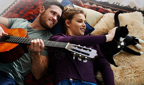 一只年轻男人弹吉他 躺在地上和女友一起躺着时 他却在玩吉他图片