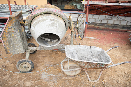 靠近在地面建筑上建造一栋房屋附近的肮脏混凝土搅拌器工人大厦机械发动机金属装修材料混合器独轮车工作图片