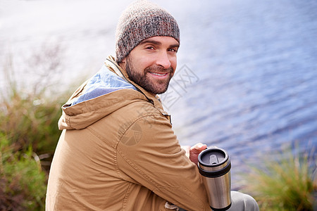 这里很棒 一个英俊男人的肖像 坐在湖边拿着热水瓶图片