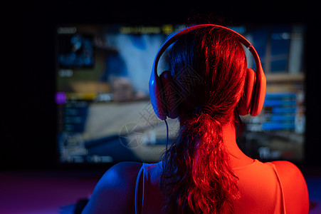 精选黑岩射手一名白人女性在黑暗中在霓虹灯下玩电脑游戏的后视图娱乐享受爱好监视器青少年卧室电脑视频键盘竞赛背景
