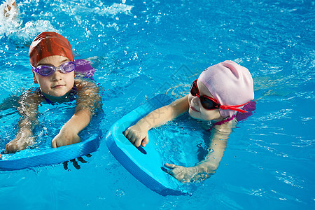 两个小女孩在室内游泳池里学游泳 用泳池板游泳教学游泳者风镜运动训练活动女孩练习班级图片
