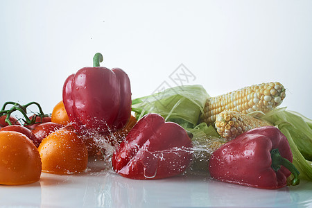 白色背景的新鲜蔬菜 西红柿 胡椒 鳕鱼玉米上喷洒图片
