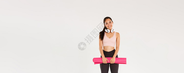 全长可爱的亚洲女孩喜欢健身 拿着橡胶垫进行锻炼或瑜伽课 穿着运动服 在健身房进行富有成效的训练后看起来很开心 锻炼很好 白色背景图片
